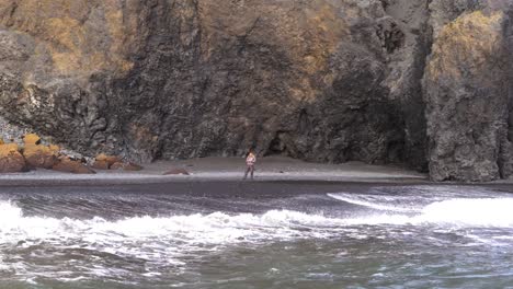 A-lone-man-on-the-black-sand-beach-in-Iceland-looks-to-the-horizon
