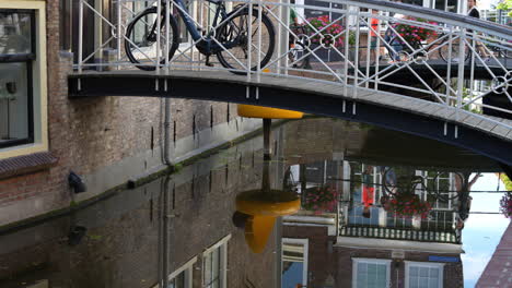 Bicycle-On-Walkway-Bridge-To-Cheese-Shop-Entrance-By-The-Canal-In-Gouda,-Netherlands