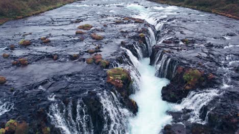 Luftaufnahme:-Umgekehrter-Überflug-Des-Bruarfoss-Kaskadenwasserfalls-Im-Süden-Islands,-Der-Mit-Der-Wunderschönen-Blauen-Kaskade-Von-Wasserfällen,-Die-In-Das-Darunter-Liegende-Tauchbecken-Münden,-Sehr-Malerisch-Ist
