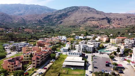Cinematic-aerial-view-of-township-and-mountain-range-in-background-in-Crete