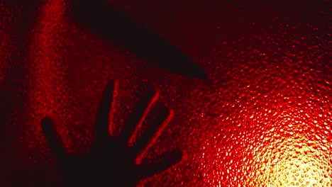 Terrifying-silhouette-of-possessed-killer-creeps-on-glass,-slowly-opens-door-in-the-dark-under-ominous-red-light