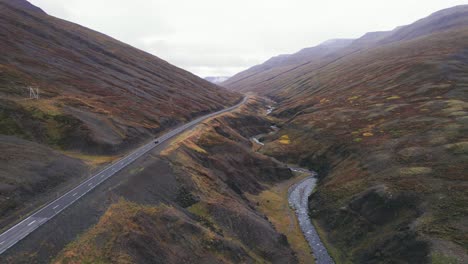 Luftbild:-Rückansicht-Eines-Schwarzen-Geländewagens,-Der-Entlang-Der-Isländischen-Ringstraße-Fährt,-Einer-Malerischen-Autobahn-Durch-Ein-Malerisches,-Abgelegenes-Fjordgebiet,-Das-In-Der-Ferne-Zu-Nebel-Und-Dunst-Führt