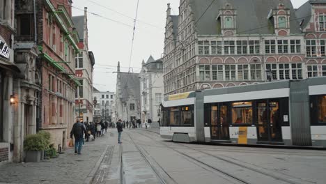 Cobblestone-street-of-Ghent-Belgium,-showcasing-tram,-historic-buildings