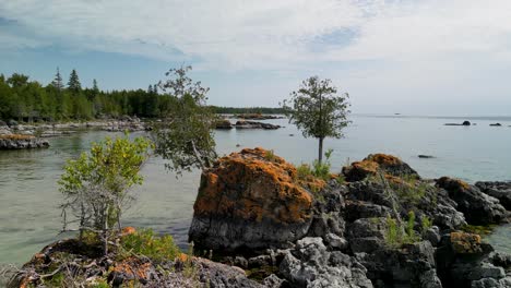 Aerial-ascent-over-large-boulders-on-lake-shoreline,-Les-Cheneaux-Islands,-Michigan