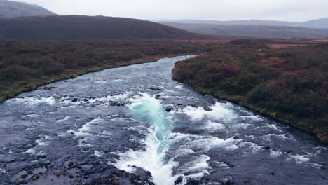 Aerial:-Reverse-reveal-Bruarfoss-cascading-waterfall-off-the-golden-circle-in-southern-Iceland-that-is-very-picturesque-with-the-beautiful-blue-cascade-of-falls-into-the-plunge-pool-below