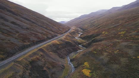 Aerial:-Reverse-reveal-of-white-SUV-on-the-Iceland-Ring-Road-which-is-a-scenic-highway-through-a-picturesque-remote-fjord-area-leading-to-fog-and-haze-in-the-distance