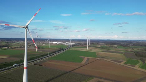 Aerial-of-wind-turbine-farm-in-fields,-high-way-crosses-the-landscape