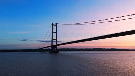 A-picturesque-spectacle-unfolds-as-Humber-Bridge-stands-adorned-in-the-colors-of-the-setting-sun,-with-cars-gracefully-navigating-its-span