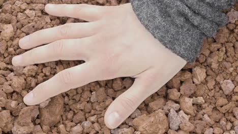Close-up-of-a-woman's-hand-sensually-touching-volcanic-gravel