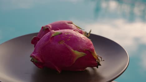 Dragon-fruit-on-a-plate-with-swimming-pool-in-the-background-at-sunset