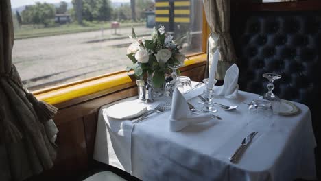 Inside-a-luxury-train-car,-a-fine-dining-table-is-elegantly-set,-exuding-opulence