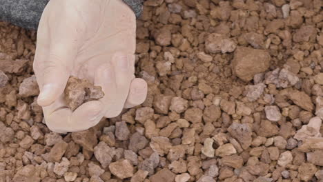 Close-up-of-a-woman's-hand-sensually-playing-with-volcanic-gravel
