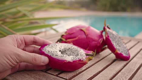 Eating-dragon-fruit-with-a-spoon-over-wood-table-in-summer-tropical-mood-POV
