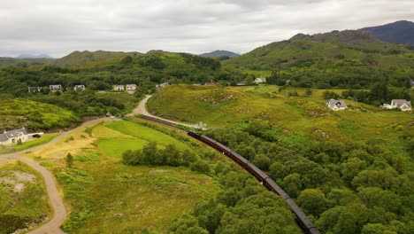 Aerial-Shot-of-Steam-Train-Moving-Through-Scottish-Highlands,-Scotland,-United-Kingdom