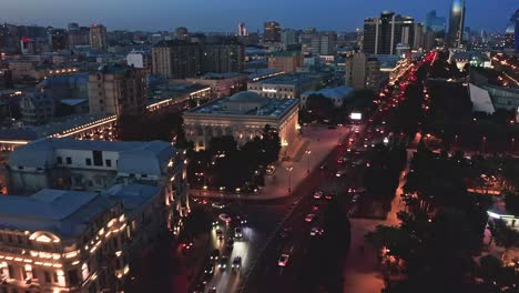 Flying-above-districts-of-Baku-modern-downtown-and-busy-streets-at-night,-Azerbaijan