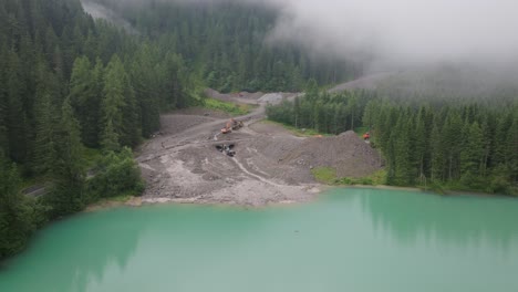 Drone-footage-showcases-the-vast-expanse-of-a-mudslide-in-the-Alps,-with-machinery-and-workers-diligently-trying-to-restore-the-terrain