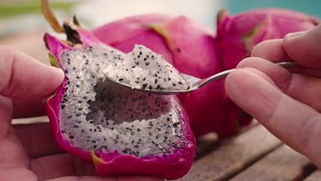 Eating-dragon-fruit-with-a-spoon-over-wood-table-in-summer-tropical-mood