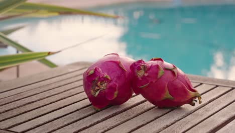 Dragon-fruit-on-wooden-table-with-swimming-pool-in-the-background-at-sunset---spinning-camera