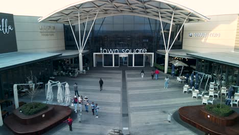 Drone-shot-of-the-Town-Square-entrance-at-The-Mall-of-Africa-with-people-walking-in-the-foreground