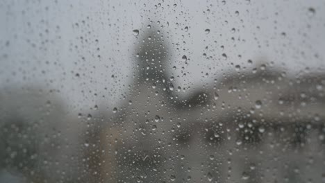 Gloomy-and-overcast-weather,-a-narrow-focus-view-of-rainy-glass-as-rain-drops-are-seen-on-a-window