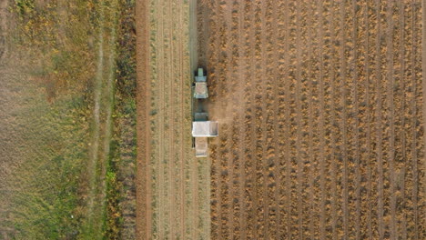 Aerial:-Slow-top-down-rising-follow-shot-of-tractor-plowing-empty-field
