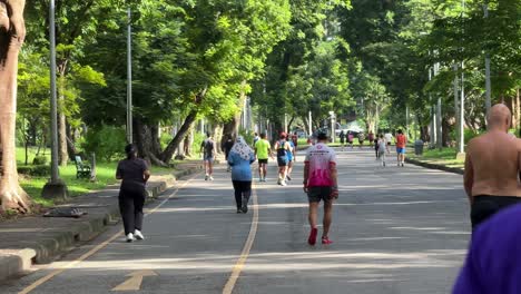 People-jogging-in-the-multi-functional-Lumpini-Park-in-Bangkok,-Thailand