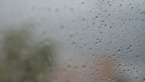 Enge-Fokusansicht-Und-Nahaufnahme-Von-Regnerischem-Glas,-Während-Bei-Trübem-Und-Bewölktem-Wetter-Regentropfen-Auf-Einem-Fenster-Zu-Sehen-Sind