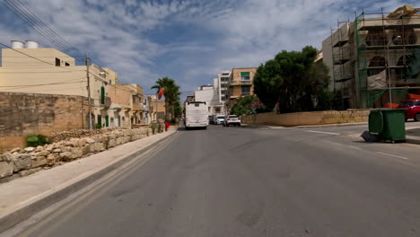 Passing-through-the-idyllic-streets-of-valletta-on-the-island-of-malta-with-views-of-the-palm-trees-on-the-roadside,-buildings-with-historic-vintage-architecture-and-an-advance-tour-bus-with-tourists