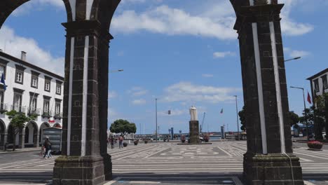 Histórica-Plaza-Principal-Portas-Da-Cidade,-Puertas-De-La-Ciudad,-A-Través-De-Arcos-En-Ponta-Delgada-Con-La-Estatua-De-Goncalo-Velho-Cabral-Al-Fondo