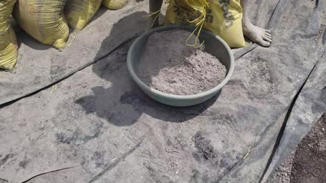 Close-up-of-a-worker-filling-an-iron-tasla-or-ghamela-with-cement-from-a-bag-at-the-construction-site