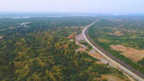 Aerial-Drone-shot-of-an-empty-railway-track-through-semi-arid-forest-valley-of-Chambal-river-in-India
