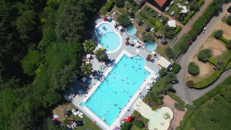 Aerial-Shot-of-Swimming-Pool-at-Weekend-Glamping-Resort-at-Campsite-Near-Lake-Garda,-Italy