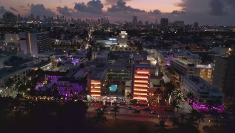 Colorful-Art-Deco-buildings-along-Ocean-Drive,-South-beach-Miami,-dusk-drone-shot