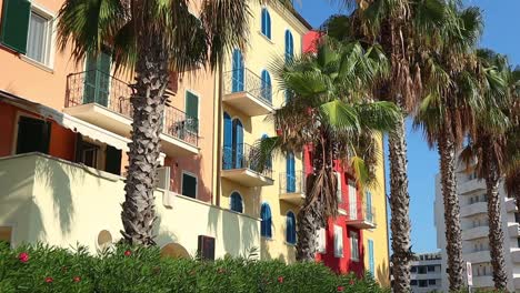 Colorful-seaside-town-in-Italy-with-palm-trees-swaying-in-the-wind