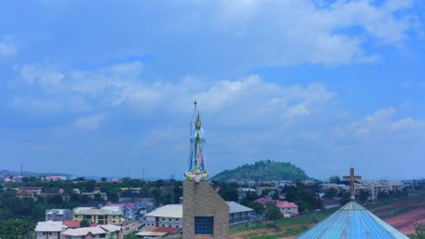 Statue-atop-a-Catholic-Church-in-Area-3-of-Abuja,-Nigeria,-aerial-reveal