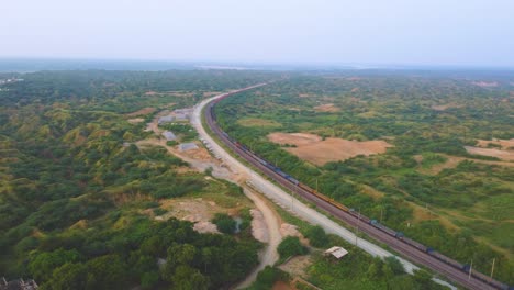 Aerial-Drone-shot-of-a-Freight-train-moving-through-semi-arid-forest-valley-of-Chambal-river-in-India