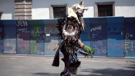 Slow-motion-shot-of-a-man-wearing-tribal-clothing-dancing-in-the-streets-of-Mexico-City