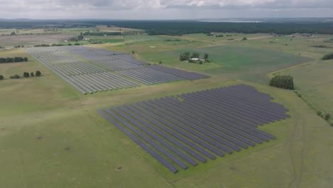 Small-sun-light-streak-hits-huge-solar-park-in-rural-Sweden-landscape,-aerial
