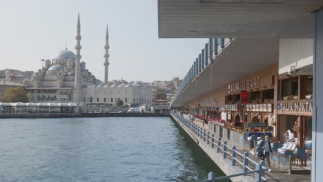Fish-restaurants-under-Galata-bridge-Turkish-city-skyline-mosque-minaret-scene