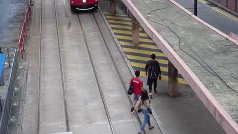 Tranvía-De-Dos-Pisos-De-Hong-Kong-Con-Librea-Roja-Pasando-Por-La-Parada-De-Tranvía-En-Causeway-Bay,-Hong-Kong