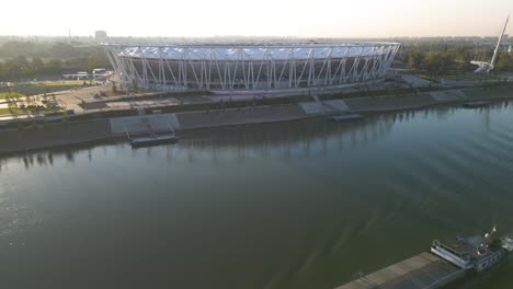 Drone-Flies-Over-Boat-on-Danube-River-to-Reveal-National-Athletic-Center,-Budapest