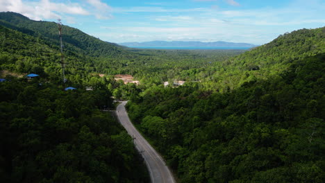 Aerial-backwards-shot-of-path-surrounded-by-tropical-hills-on-Koh-Phangan,-Thailand