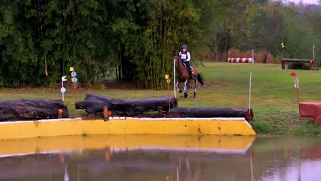 A-horse-and-rider-jumping-over-an-obstacle-into-the-water-during-a-cross-country-race