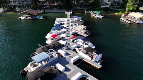 community-of-lakeside-homes-following-down-a-boat-dock-and-revealing-large-mansions-with-people-enjoying-the-day-on-the-lake-Arrowhead-in-california-AERIAL-DOLLY-BACKWARDS-RAISE-TILT