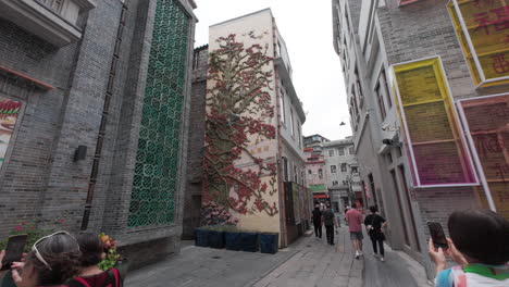 Chinesischer-Tourist-Fotografiert-An-Der-Wunderschön-Dekorierten-Wand-Eines-Gebäudes-In-Einem-Neuen,-Revitalisierten-Touristengebiet