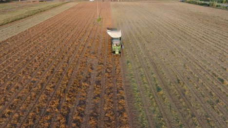Aerial:-Flying-backwards-in-front-of-a-tractor-plowing-the-soil