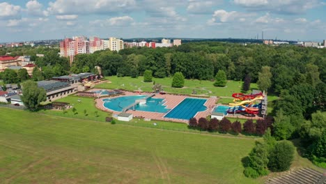 Aerial-drone-shot-of-aqupark-in-the-middle-of-city-with-pools-and-water-slides-during-summer