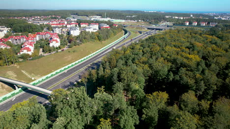 Aerial-orbit-around-multi-lane-highway-below-suburban-apartment-complex-and-dense-forest