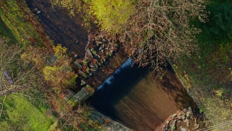 Aerial-drone-top-shot-of-creek-sluice-and-river-during-sunny-autumn-fall-day