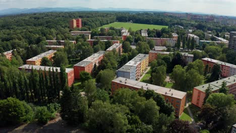 Aerial-drone-shot-of-flat-apartment-complex-with-park,-forest-and-Beskydy-mountains-view